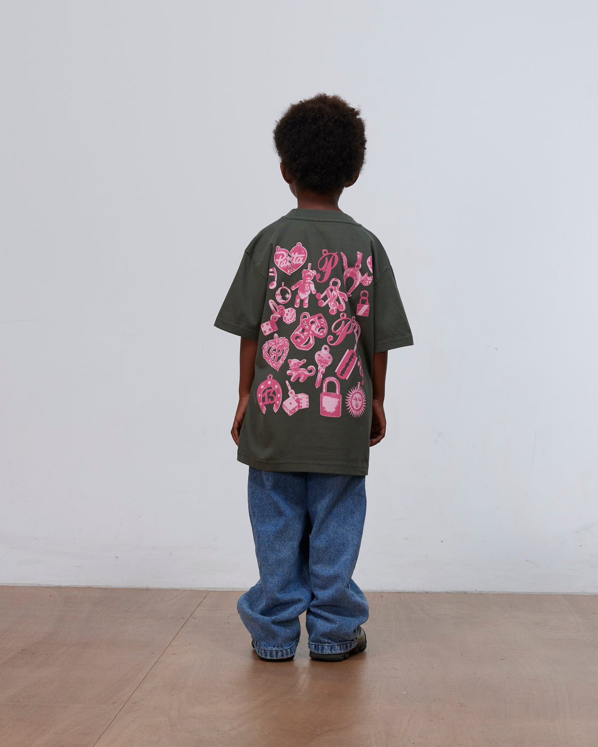 Back view of a kid wearing the green Patta Kids Charm T-Shirt with pink charms print.